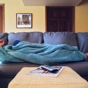 Cold person laying on the couch under a blanket.