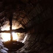 Large dirty duct with cross fan at end and sun shining in.