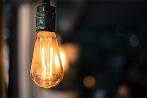 Stylized, lit light bulb hanging in a home.
