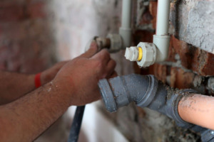 Plumber adding hot and cold water lines to basement utility room.
