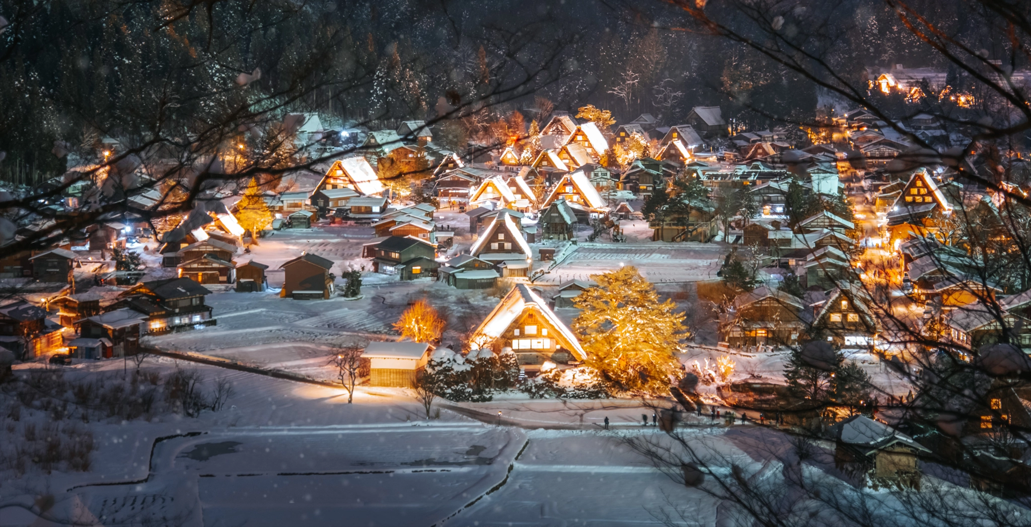 A snow-covered village with houses featuring exterior lighting.