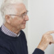 Smiling Senior Man Adjusting Central Heating Thermostat