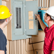 Two electricians inspecting an electrical panel.