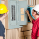 Two electricians inspecting an electrical panel.