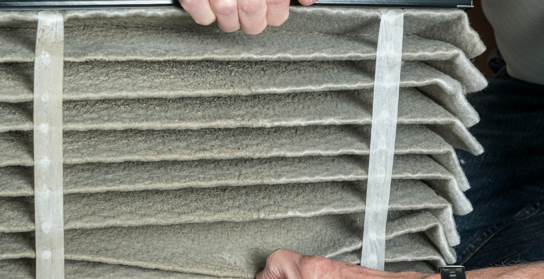 An air conditioning technician inspecting dust in a dirty air filter.