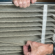 An air conditioning technician inspecting dust in a dirty air filter.