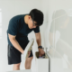 A man inspecting the tank of his toilet for issues.